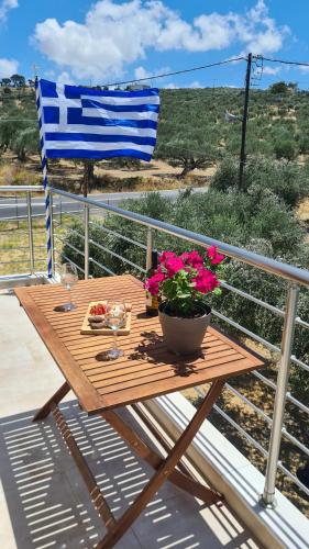 a wooden table with a bowl of flowers and a flag at The Olive's Whisper in Skalánion