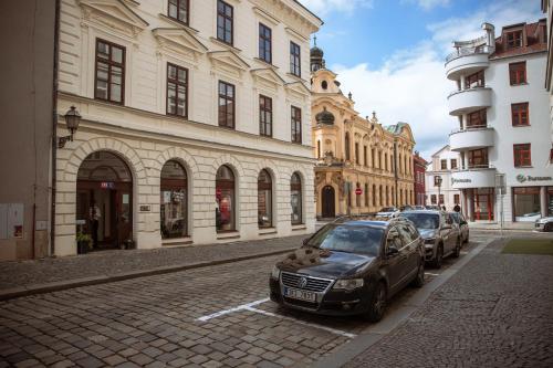 two cars parked on a street in front of buildings at Luxusní apartmán 3KK u náměstí - Klicperova in Hradec Králové