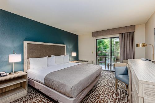 a hotel room with a bed and a balcony at Rivers Edge Motel in Cherokee
