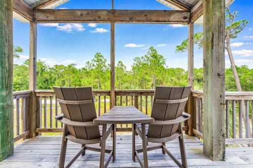 two chairs and a table on a porch with a gazebo at The Floridian, Old Florida Charm with Modern Comfort in St. George Island