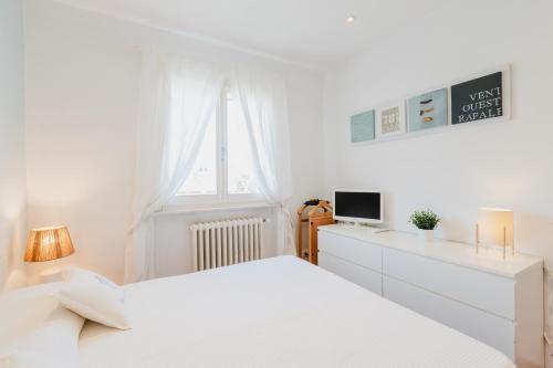a white bedroom with two beds and a window at Maison Cir&igrave; in Forte dei Marmi
