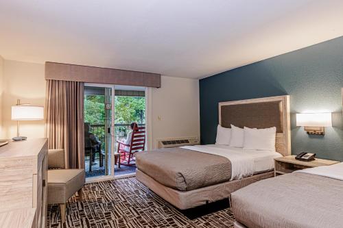 a hotel room with two beds and a balcony at Rivers Edge Motel in Cherokee
