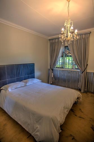 a bedroom with a large bed and a chandelier at Pavetta Country House in Magoebaskloof