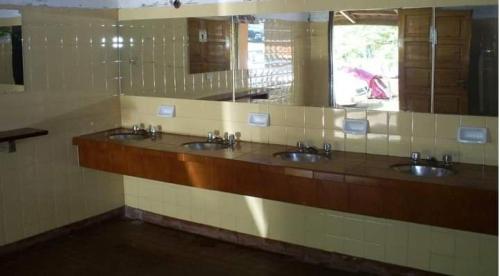 a public bathroom with three sinks and a mirror at La Ribera Hotel Dormis Camping in Villa Carlos Paz