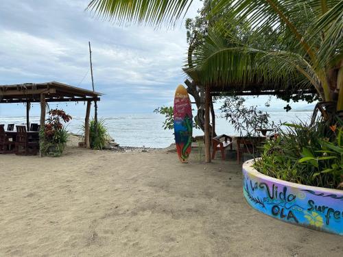 a surfboard sitting on the beach near the ocean at Cabaña Buganvilia Punto Surf Barra La Saladita in La Salada