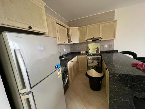 a kitchen with a white refrigerator and a black counter top at Ain Sokhna Chalet in Ain Sokhna
