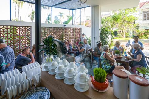 Un grupo de personas sentadas alrededor de una mesa con jarrones. en Hoi An Grace River Villa, en Hoi An