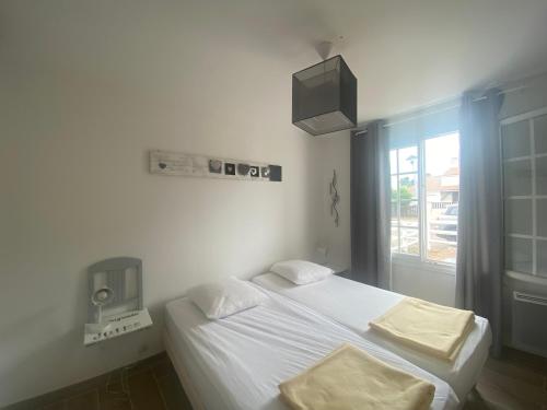 Cette chambre comprend un lit avec des draps blancs et une télévision. dans l'établissement Maison proche plage, au calme, Wi-Fi, jardin, animaux acceptés - FR-1-22-318, à La Tranche-sur-Mer