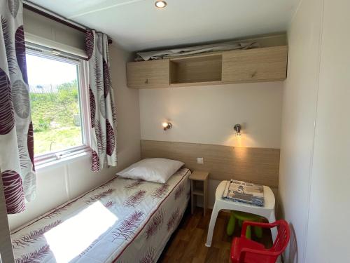 Cette petite chambre comprend un lit, un bureau et une fenêtre. dans l'établissement Mobil-home 3 chambres proche plage à Fouras, idéal 6 pers., équipement complet, calme assuré. - FR-1-709-68, à Fouras