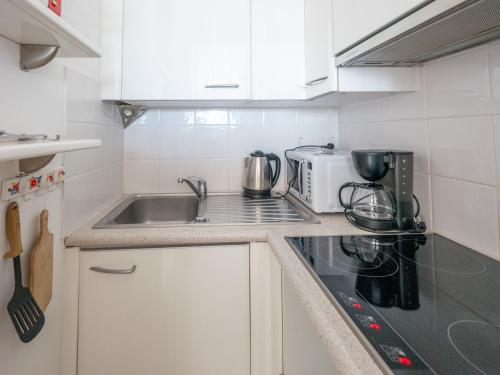 une petite cuisine avec un évier et une cuisinière dans l'établissement Studio 2 pers accès plage direct, balcon - FR-1-197-584, à Les Sables-dʼOlonne