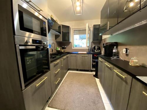 une cuisine avec des appareils électroménagers en acier inoxydable et des armoires noires dans l'établissement Maison familiale et spacieuse, à Montpellier