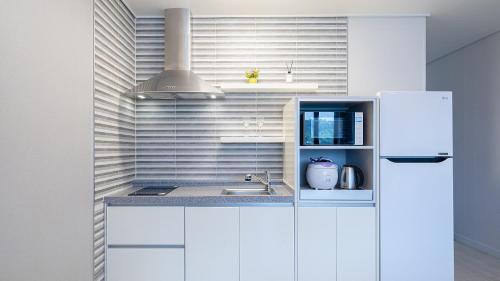 a white kitchen with a sink and a refrigerator at Yeosu View Foret Pension in Yeosu