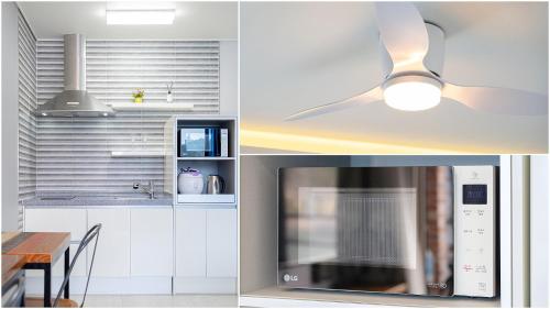 a kitchen with white cabinets and a ceiling fan at Yeosu View Foret Pension in Yeosu