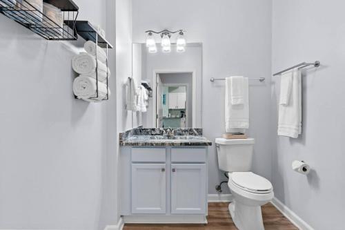 a white bathroom with a toilet and a sink at 1st Floor Palms of Destin Resort Updated Condo with Beach Shuttle in Destin