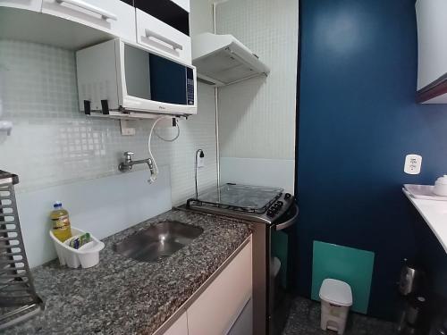 a small kitchen with a sink and a microwave at Flat Atlântico Meireles by Escala in Fortaleza