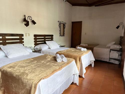 a bedroom with two beds with white sheets at Hotel Casa Blanca Antigua Guatemala in Antigua Guatemala