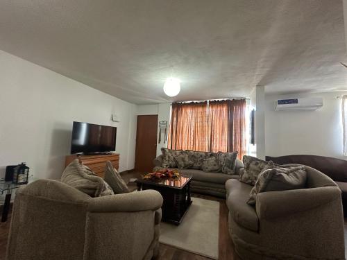 a living room with couches and a flat screen tv at Departamento en fraccionamiento para 4 personas, cuenta con todo para estancias largas, seguridad y estacionamiento, zona céntrica, bancos,garitas,plazas in Rancho Mesa de Tijuana