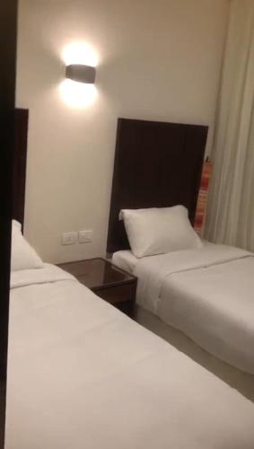a hotel room with two beds and a lamp at Porto golf marina in El Alamein