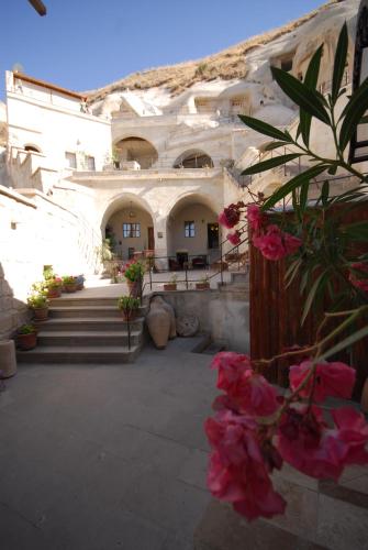 a large building with pink flowers in a courtyard at Vezir Cave Suites in Goreme