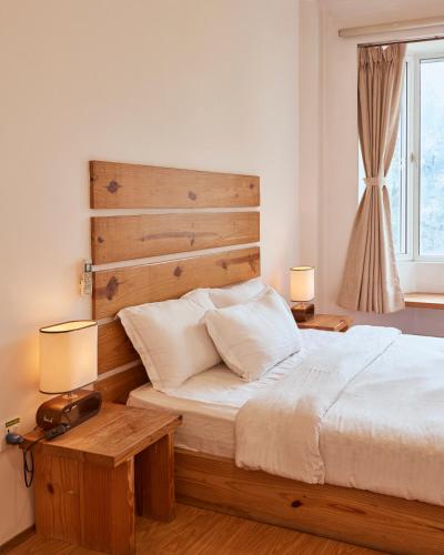 a bedroom with a bed with a wooden headboard and two lamps at Ananya Apartments Phase 1 in Kathmandu