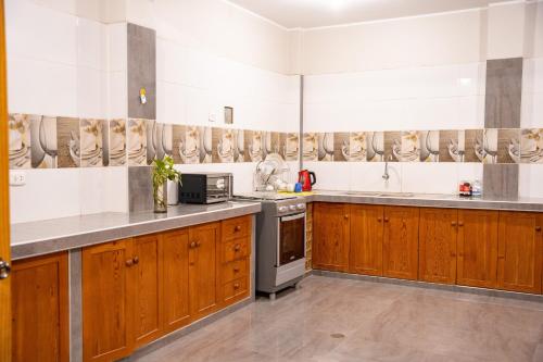 una cucina con armadietti in legno ed elettrodomestici in acciaio inossidabile di Hostal Los Balcones II a Nazca