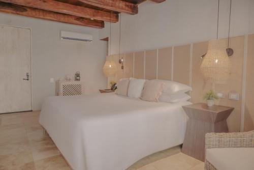 a white bedroom with a large white bed and a table at Hotel Casa Don Luis by Faranda Boutique, a member of Radisson Individuals in Cartagena de Indias