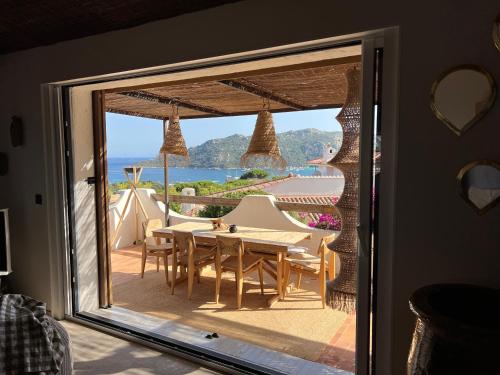 Cette chambre dispose d'une porte coulissante en verre avec une table et des chaises. dans l'établissement Villa LILY BAY baie de Santa Giulia-Porto Vecchio, à Porto-Vecchio