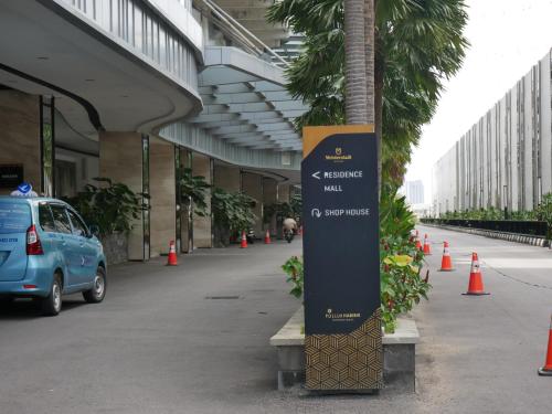 a sign in front of a building with a palm tree at Meisterstadt Pollux Habibie in Batam Center