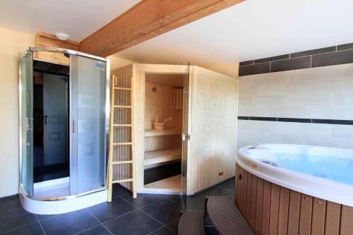 Chalet luxe 13 personnes SPA SAUNA VOSGES-GERARDMER في لو ثولي: حمام كبير مع حوض استحمام ودش