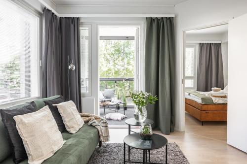 a living room with a green couch and a window at Arctic Pine City Suite in Rovaniemi