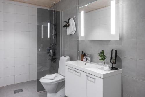 a white bathroom with a toilet and a sink at Arctic Pine City Suite in Rovaniemi