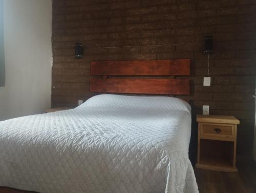 a bed with a wooden headboard and a night stand at Cabaña paraíso in Los Espinos