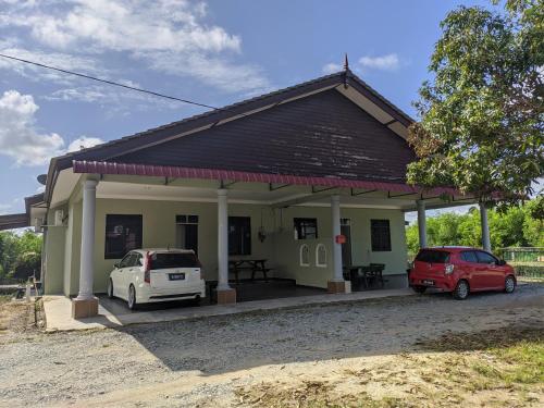 a small house with two cars parked in front of it at Homestay Ayah Ngah Marang in Marang