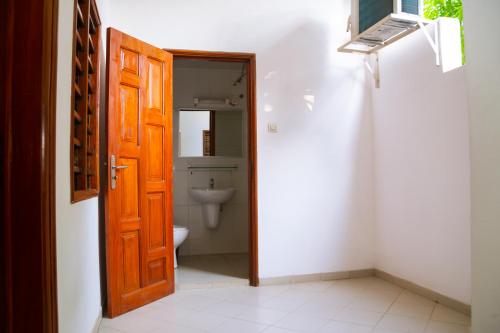 a bathroom with a toilet and a wooden door at JRéside Belle Rouge 40m2 centre-ville in Cotonou