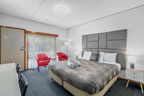 a bedroom with a large bed and red chairs at Comfort Inn Benalla in Benalla