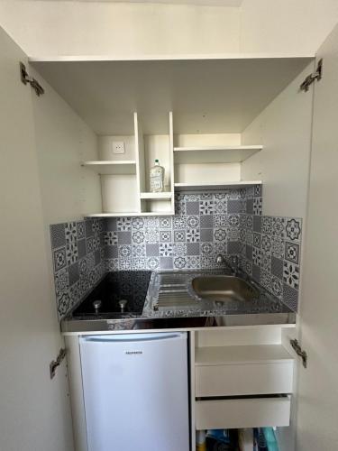 une petite cuisine avec un évier et un réfrigérateur dans l'établissement Mora, à Enghien-les-Bains