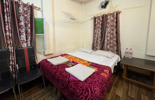 a small room with a bed with two towels on it at The Golden Lodge Varanasi in Varanasi