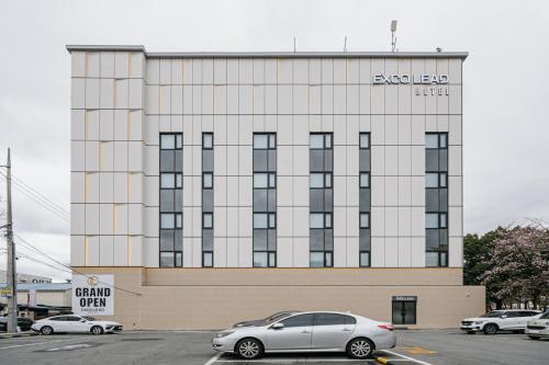 a building with cars parked in a parking lot at Daegu Exco Lead Hotel in Daegu
