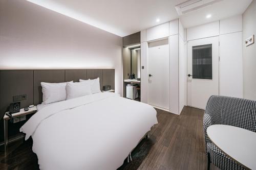 a bedroom with a large white bed and a chair at Daegu Exco Lead Hotel in Daegu