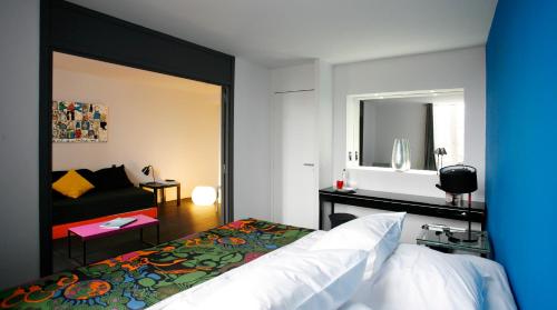 a bedroom with a bed and a couch and a mirror at Design Hôtel des Francs Garçons in Saint-Sauvant