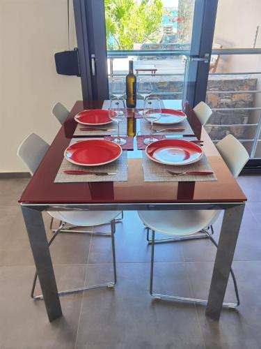 a dining room table with red plates and wine glasses at Andromeda Sea View Villa in Epáno Eloúnda