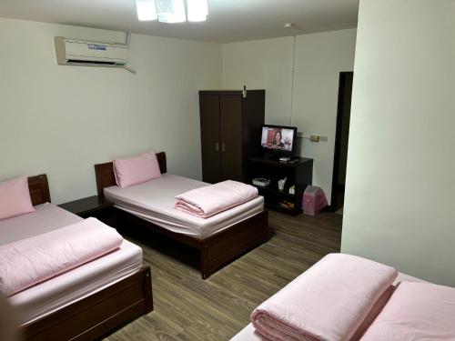 a room with two beds and a tv in it at 今友緣二館民宿 in Dongyin