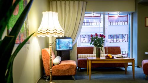 a living room with a lamp and a chair and a table at ARIBĖ Hotel Klaipėda, Free parking in Klaipėda