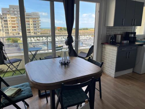 a table and chairs in a kitchen with a large window at Normandy trip 5 min à pied de la plage in Courseulles-sur-Mer