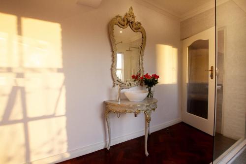 a dressing table with a mirror and a vase of flowers on it at The Great Gatsby Houghton in Johannesburg