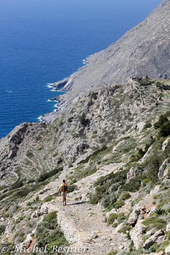 a man walking up a mountain with the ocean at Dorana Apartments & Trekking Hotel in Diafani