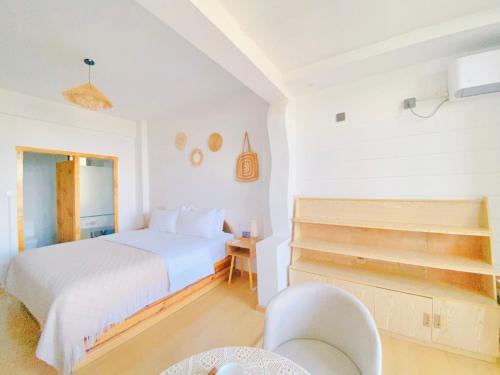 a white bedroom with a bed and a chair at Dali Erhai Forest River View Hostel in Dali