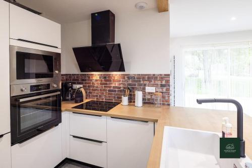 une cuisine avec des armoires blanches et un four à plaques de cuisson dans l'établissement L'Ecrin de Soligny gîte 5 pers, à Soligny-les-Étangs