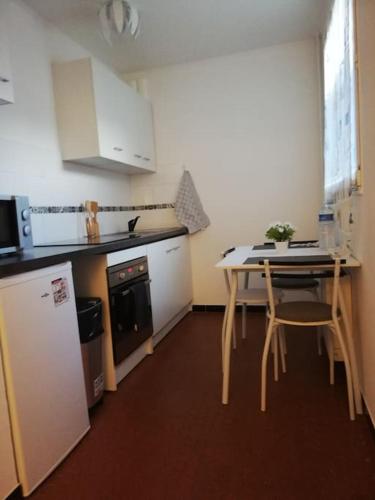 une petite cuisine avec une table et un réfrigérateur dans l'établissement Logement entier tout confort, à Saint-Cyr-lʼÉcole