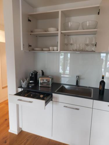 a kitchen with white cabinets and a sink at Wohnstation Princess Suite in Subingen